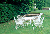 Seating group of white furniture on the lawn, steps, hedge