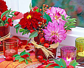 Dahlia (Dahlien), Rosa (Hagebutten), rote Gläser, Bastschleifen, Windlichter