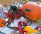 Metal rocking horse with wreath of pink (rose hip), Parthenocissus