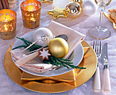 Plate decoration with golden place plate, white napkin and Christmas tree decorations