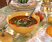 Yellow soup tureen with pumpkin soup, decorated with parsley and cream