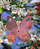 Flower shaped copper pendant on branch of malus (apple)