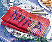 Lavandula (Lavendel) zu Namen 'Nina' gelegt auf roter Serviette