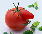 Tomate mit 'Nase' als Gesicht mit Hagebuttenscheibe als Auge und grünem Chili als Mund