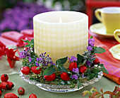 Wreath of nepeta (catmint), pink (rose hips) around white candle