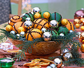 Citrus (Orangen, Limetten), Gewürznelken, silberne Weihnachtsbaumkugeln, Zweige