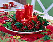 Adventskranz aus Ilex (Stechpalme) mit roten Kerzen auf weißem