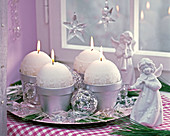 Adventskranz aus silbernen Töpfen mit runden weißen Kerzen, Glaskugeln
