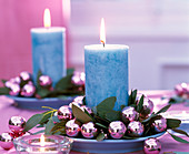 Kranz aus Eucalyptus, rosa Weihnachtsbaumkugeln um blaue Kerze auf