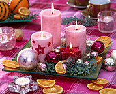 Advent wreath made of three pink and one red pillar candle on a square base