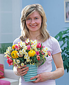 Young woman with bouquet of Narcissus (daffodils), Tulipa (tulips)