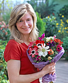 Junge Frau mit Strauß aus Anemone coronaria (Kronenanemone)