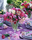 Strauß aus Tulipa (Tulpen) in Glasvase auf gedecktem Tisch