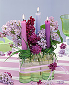 Syringa in small bottles with wreaths of grass as a candle holder
