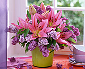 Bouquet of lilium (lily) and syringa (lilac) in green vase
