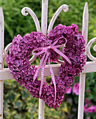 Herz aus violettem Syringa (Flieder) an weißem Metallzaun