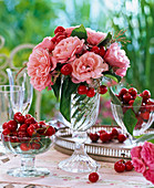 Strauß aus Rosa (Rosen), Prunus (Kirschen) und Gräsern in Glasbecher, Schale