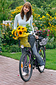 Junge Frau mit Fahrrad hat Helianthus (Sonnenblumen)