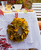 Kranz aus Herbstlaub von Prunus (Kirsche) seitlich an gedecktem Tisch