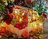 Rosa (Rosen), Hydrangea (Hortensien), Windlichter in Korb aus Holz