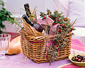 Korb mit Pernettya (Torfmyrte), Weinflaschen, dekoriert