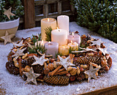 Kerzen in Kranz aus Picea (Fichtenzapfen), Zimtstangen, Arachis (Erdnüssen)