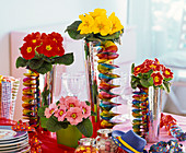 Carnival table decoration with Primula (primroses), streamers, coloured tinsel