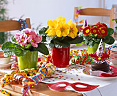 Faschings - Tischdekoration mit Primula (Primeln), Luftschlangen, Krapfen