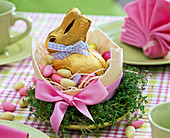 Ostrich egg as Easter nest with chocolate Easter bunny, sugar eggs, bow