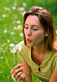 Woman blowing Taraxacum (dandelion) seed head