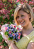 Woman with bouquet of Rosa 'Mini Eden' (roses), Myosotis (forget-me-not) and Corylus