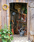 View through open door into the tool house with tools, wheelbarrow, pots