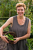 Woman with freshly harvested cucumis (mini cucumbers) in wicker basket