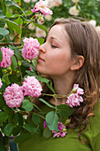 Woman sniffs at Rosa 'Gertrude Jekyll' (English fragrance rose)
