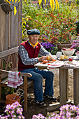 Grandfather sitting at the table peeling Malus (apples)