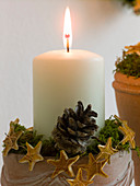 Candle with moss, cones and stars made of orange peel