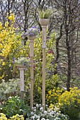 Handmade pottery planters on sticks stuck into the flower bed