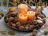 Blechteller mit Walnüssen und Kerzen auf Tisch