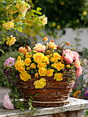 Homemade wicker basket with arrangement of pink (mini roses) and oregano