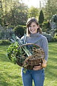 Young woman holding wicker basket with vegetables