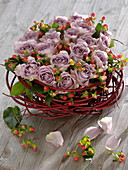 Arrangement of purple roses and St. John's wort fruits in wreath of dogwood branches