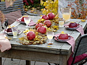 Tischdekoration mit Granatäpfeln auf einem Läufer aus Herbstlaub