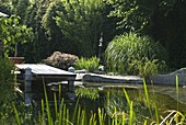 Swimming pond with wooden footbridge bordered with granite blocks