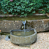 Wasserspiel: Steintrog, umgeben von Kräutern im Kräutergarten neben dem Haus.
