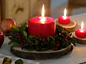 Rote Kerzen auf Holzscheiben, Kranz aus Ilex (Stechpalme)