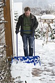 Mann räumt Schnee mit einer Schneelady