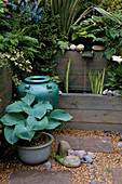 Wasserspiel mit blauem Keramiktopf und Container mit Hostas