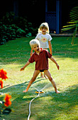 Robert AND HAZEL PLAYING with A HOSEPIPE On THE LAWN. THE NICHOLS Garden, READING