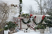 Winter balcony with conifers, bird feeder house, snow and garland
