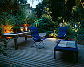 Terrassenterrasse mit Beleuchtung: Blaue Liegestühle, blauer Tisch, Holztisch mit Kerzen, Bambus (Musa basjoo), und Agave